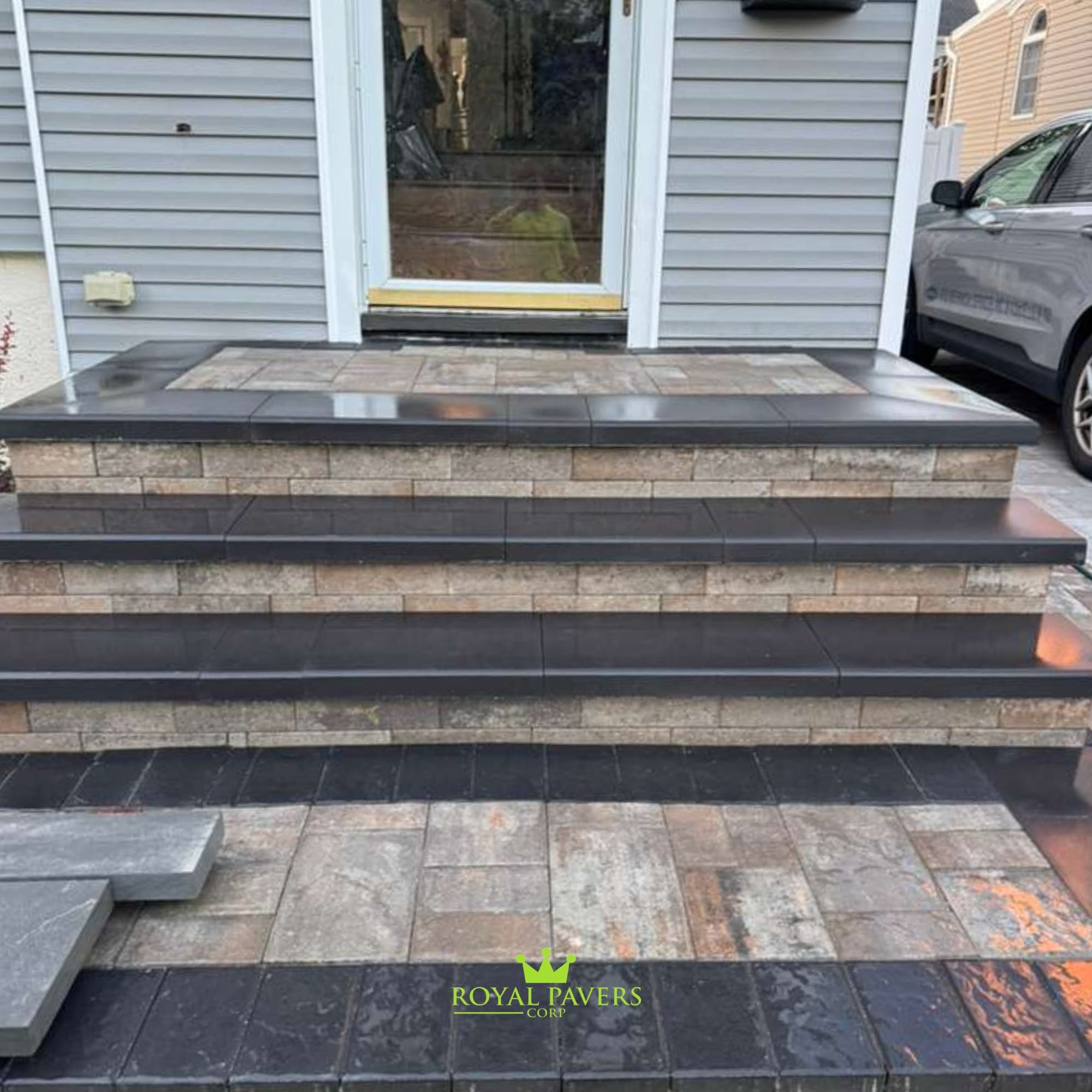 Detailed close-up of custom front steps featuringStacked stone risers, dark stone treads, and a modern paver walkway, Long Island by Royal Pavers Corp