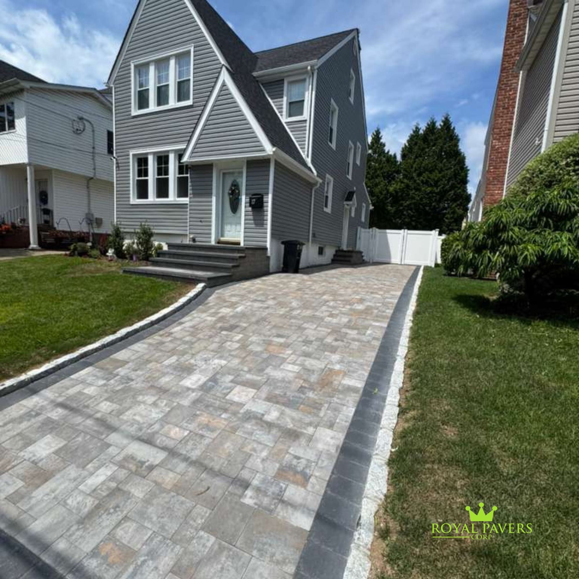 Detailed view of custom interlocking paver driveway with clean black paver border and matching stoop steps in Long Island by Royal Pavers Corp