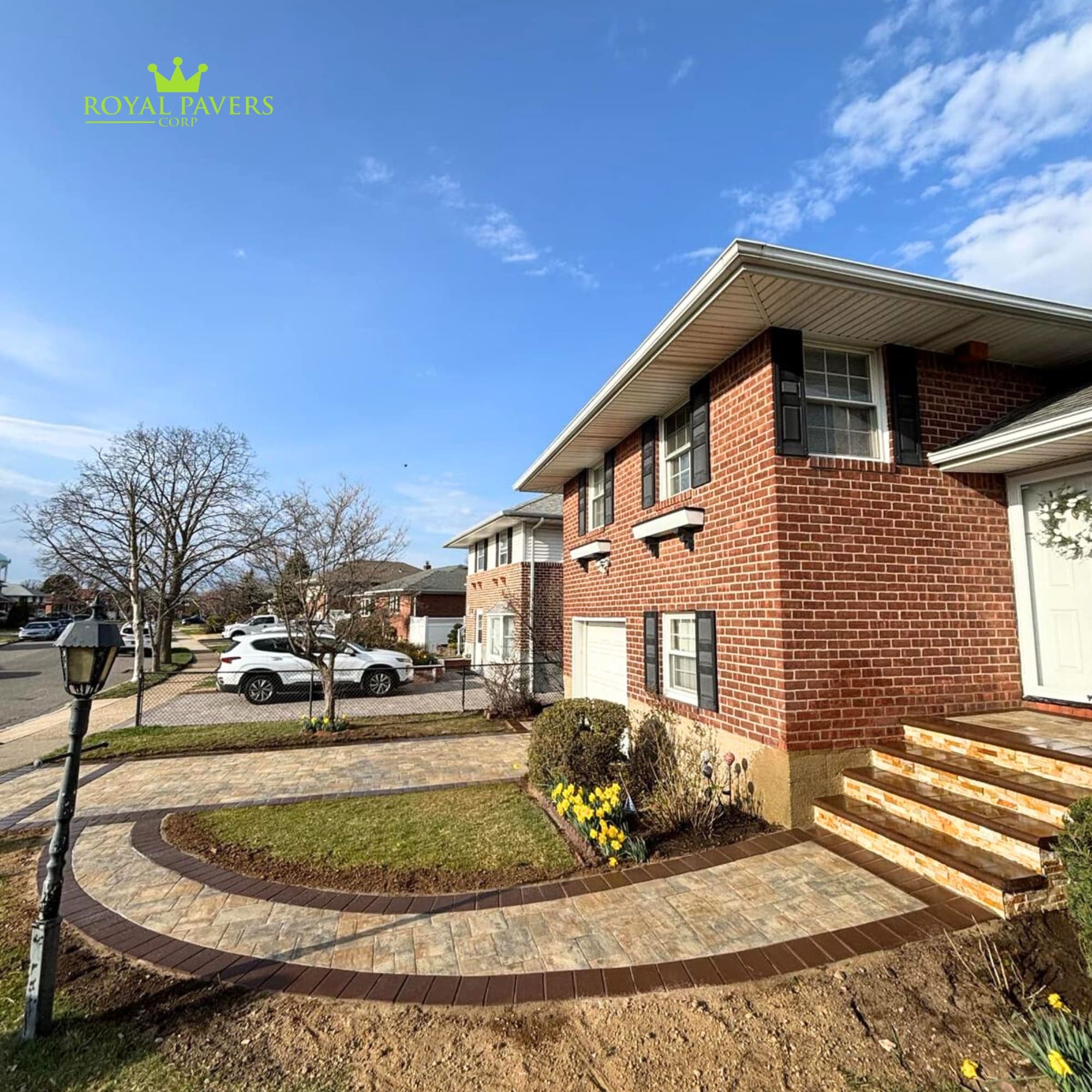 Multi-color paver driveway and path with elegant dark border curve in front of a brick house in Long Island by Royal Pavers Corp